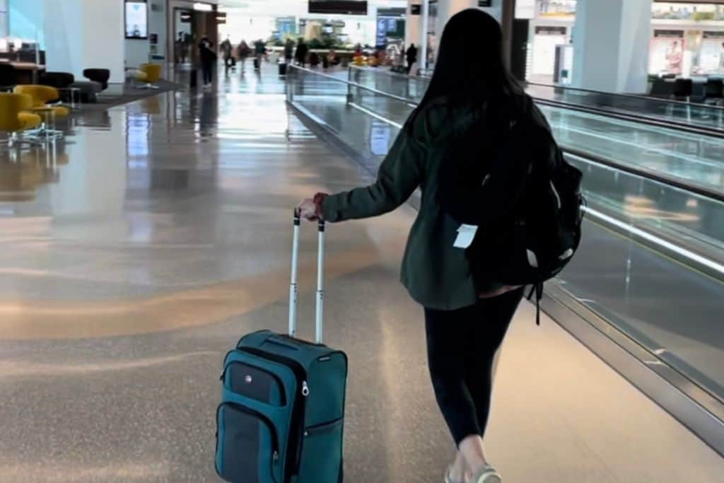 A woman with long black hair rolling her bag to her gate at the airport