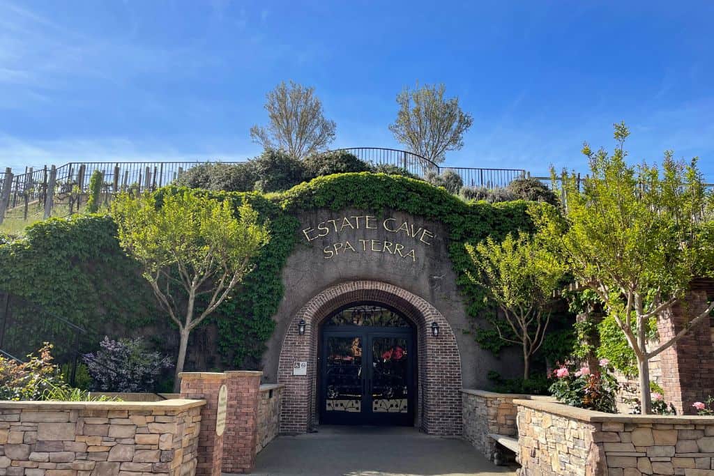 The outside of a cave spa that is covered in vines and gardens